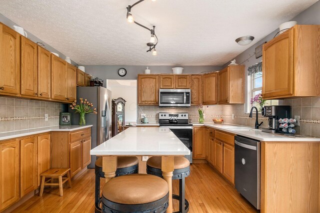 kitchen with light wood-type flooring, a sink, appliances with stainless steel finishes, and tasteful backsplash