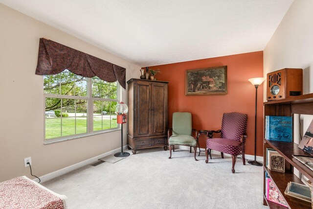 sitting room with baseboards, light colored carpet, and visible vents