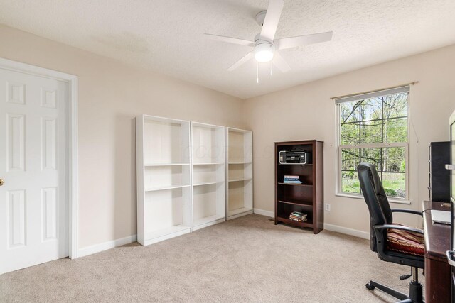 office space featuring baseboards, a ceiling fan, a textured ceiling, and light colored carpet