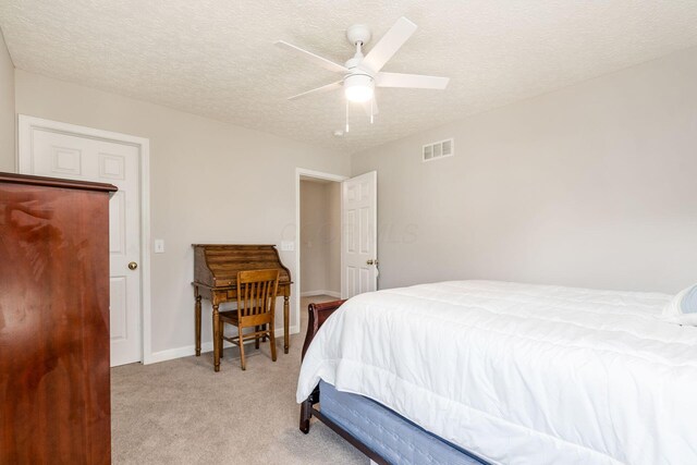 bedroom featuring visible vents, a textured ceiling, ceiling fan, and light carpet