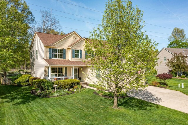 traditional-style home featuring a porch, concrete driveway, a shingled roof, and a front yard