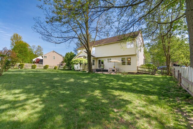 back of house with a lawn and a fenced backyard