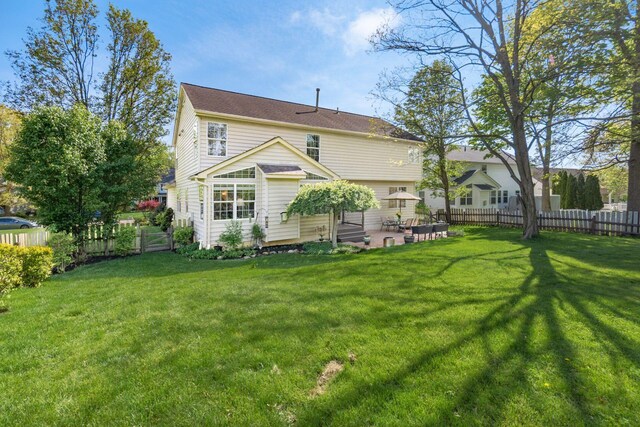 back of property with a yard, a fenced backyard, and a patio area