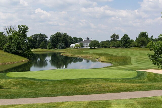 view of home's community with a water view, view of golf course, and a yard