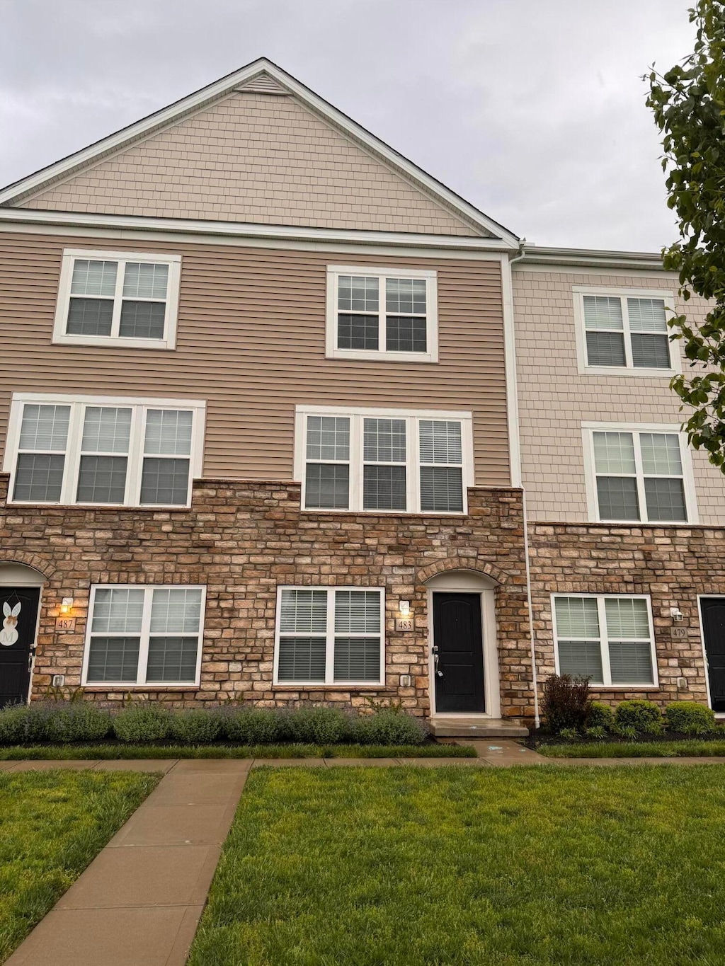 multi unit property featuring a front yard and stone siding