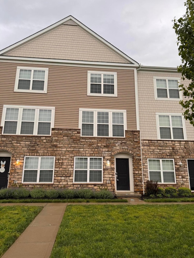 multi unit property featuring a front yard and stone siding