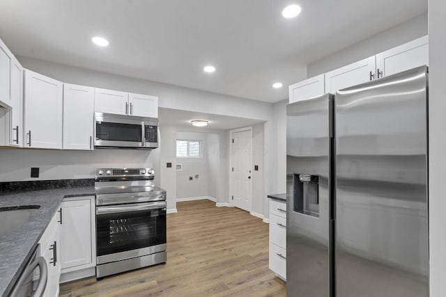 kitchen with baseboards, appliances with stainless steel finishes, and white cabinets
