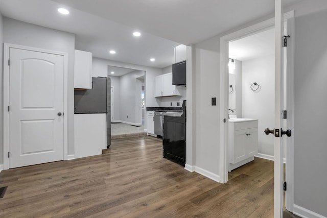 kitchen with freestanding refrigerator, white cabinets, dark wood-style floors, and dark countertops