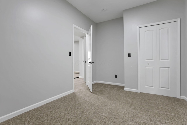 unfurnished bedroom featuring baseboards, carpet, and a closet