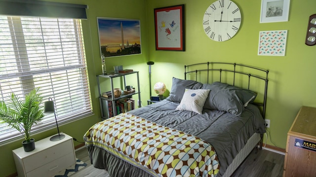 bedroom featuring baseboards, multiple windows, and wood finished floors