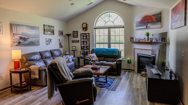 living room featuring a fireplace, vaulted ceiling, wood finished floors, and visible vents