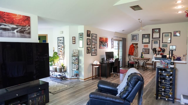 living room featuring baseboards, visible vents, wood finished floors, and vaulted ceiling
