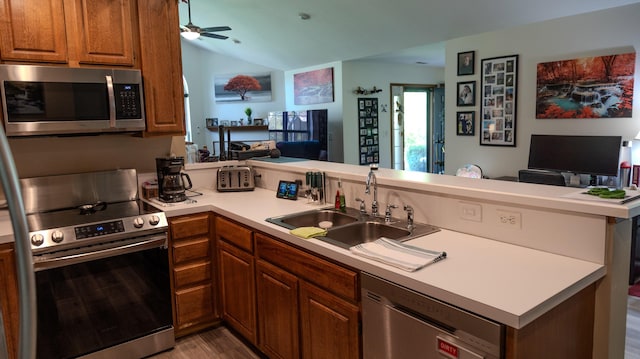 kitchen with a peninsula, open floor plan, appliances with stainless steel finishes, and a sink