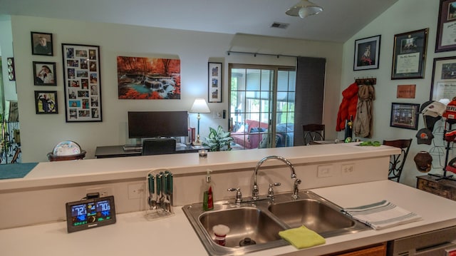 kitchen with visible vents, lofted ceiling, open floor plan, light countertops, and a sink