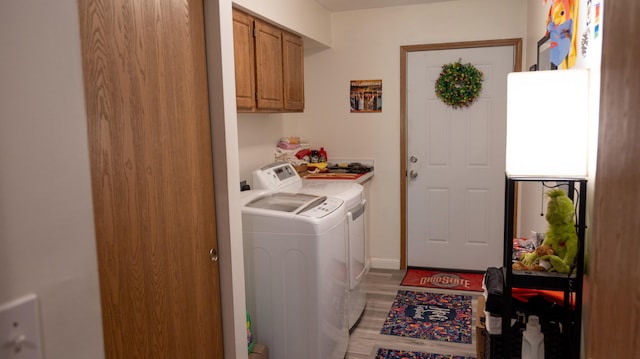 washroom featuring cabinet space, washer and clothes dryer, and light wood-style flooring
