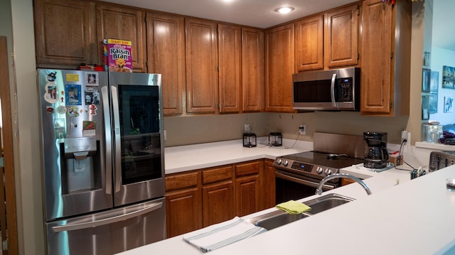 kitchen with light countertops, appliances with stainless steel finishes, brown cabinetry, and recessed lighting