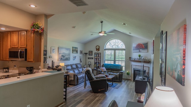 living room with visible vents, wood finished floors, lofted ceiling, ceiling fan, and a tile fireplace