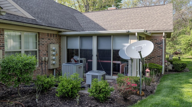 details with brick siding, a shingled roof, central air condition unit, and a downspout