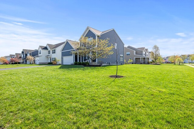 view of side of property featuring a lawn, an attached garage, board and batten siding, and a residential view