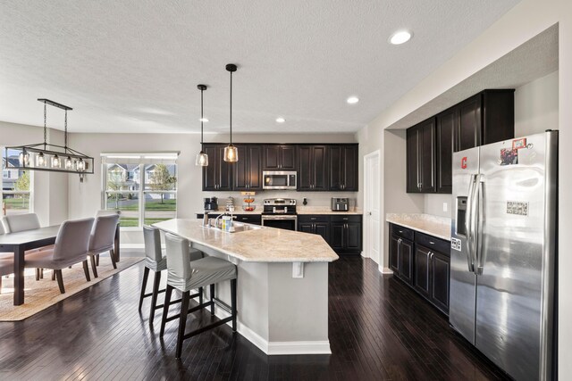 kitchen featuring a sink, baseboards, stainless steel appliances, and dark wood-style flooring