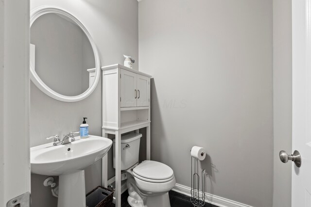 bathroom with a sink, baseboards, and toilet