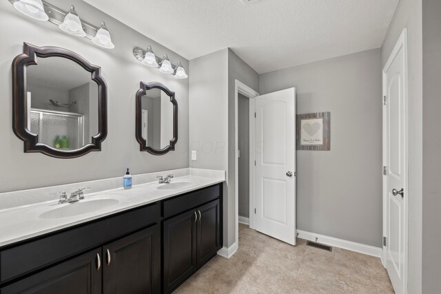 bathroom featuring visible vents, a sink, baseboards, and a textured ceiling