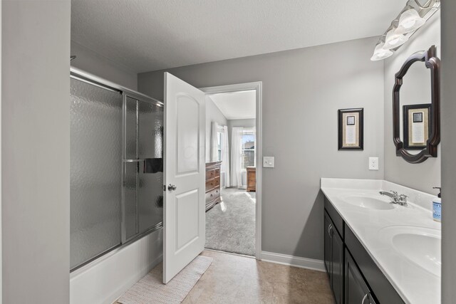 bathroom with a sink, bath / shower combo with glass door, baseboards, and double vanity