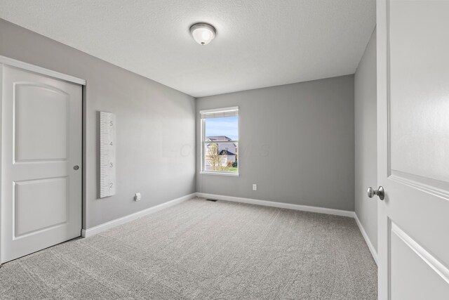 carpeted spare room with baseboards and a textured ceiling