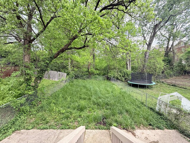 view of yard with a trampoline and fence