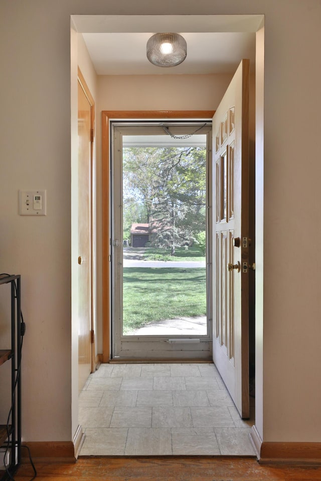 doorway to outside with baseboards and light wood finished floors