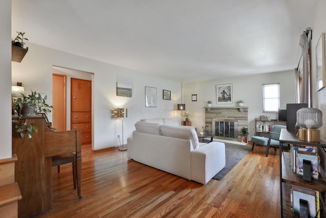 living area with a glass covered fireplace, baseboards, and light wood finished floors