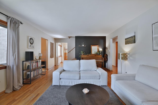 living room featuring stairway, baseboards, and light wood finished floors