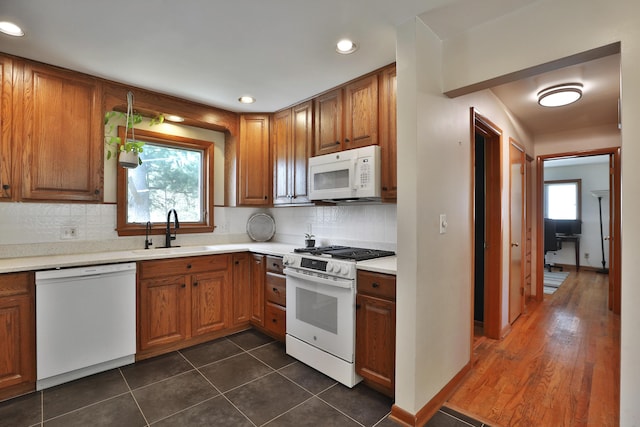 kitchen featuring a sink, tasteful backsplash, white appliances, and a wealth of natural light