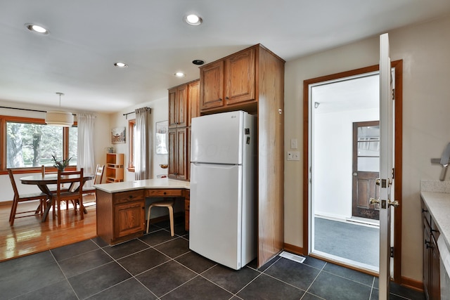 kitchen featuring recessed lighting, freestanding refrigerator, brown cabinets, and visible vents