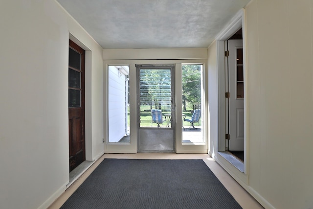 doorway to outside featuring baseboards and carpet