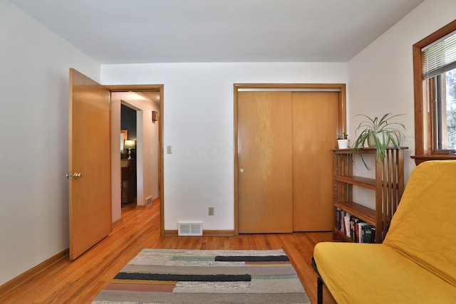 living area with baseboards, wood finished floors, and visible vents