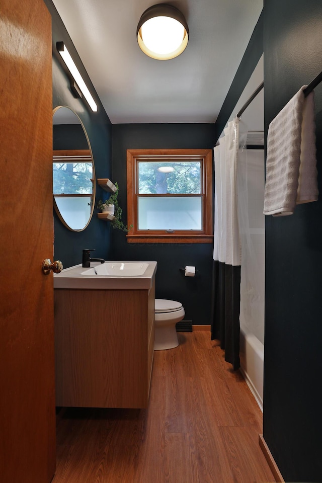 bathroom featuring toilet, wood finished floors, shower / tub combo with curtain, and vanity