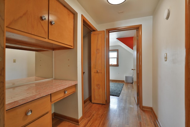 interior space featuring baseboards, lofted ceiling, and light wood finished floors