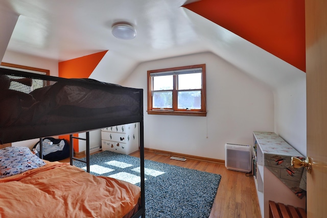 bedroom with baseboards, vaulted ceiling, and wood finished floors