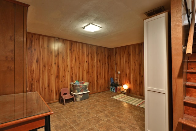 misc room featuring a textured ceiling, wood walls, and visible vents