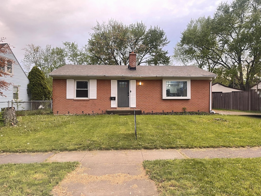 ranch-style house with brick siding, fence, and a chimney
