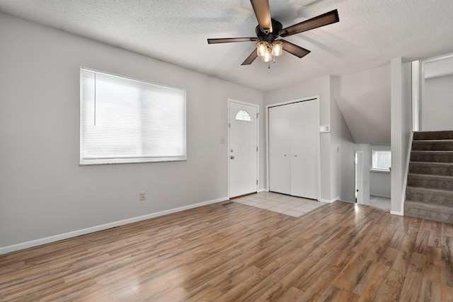 foyer entrance featuring wood finished floors, stairway, a ceiling fan, plenty of natural light, and a textured ceiling