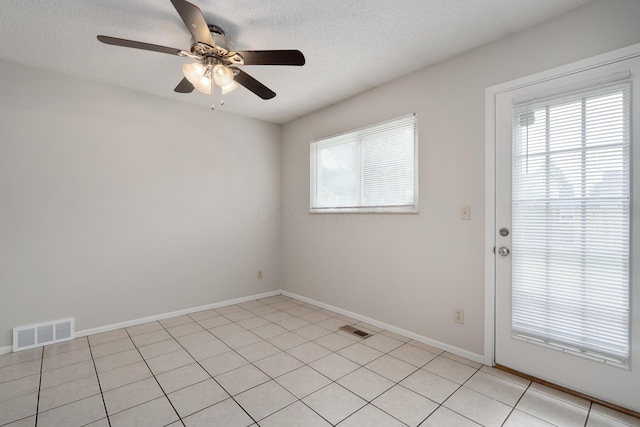 unfurnished room with ceiling fan, baseboards, light tile patterned floors, and a textured ceiling