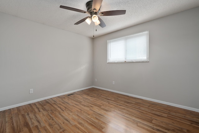 spare room with wood finished floors, a textured ceiling, baseboards, and a ceiling fan