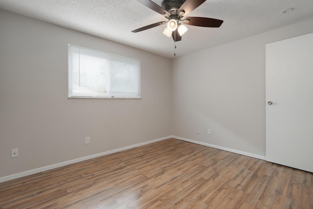 spare room with wood finished floors, a ceiling fan, a textured ceiling, and baseboards