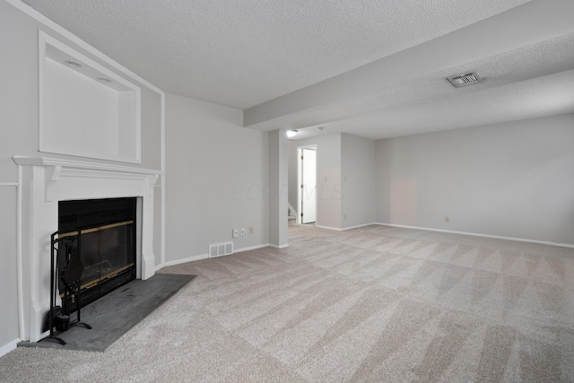 unfurnished living room with a textured ceiling, carpet floors, stairway, a glass covered fireplace, and baseboards