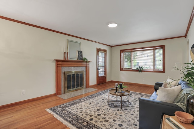 living room featuring a fireplace, crown molding, baseboards, and light wood-style floors