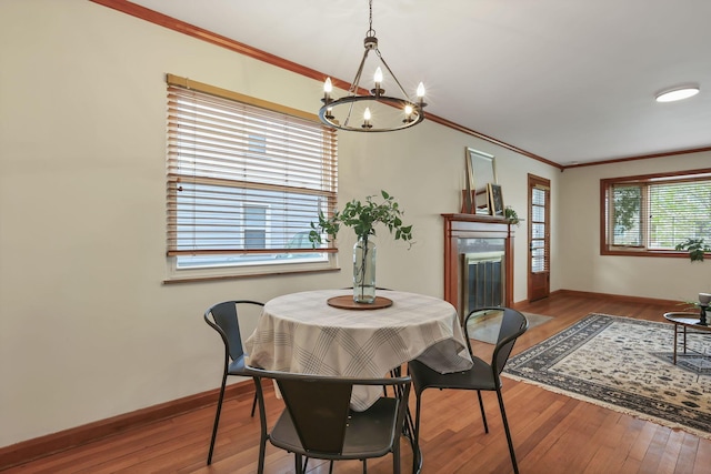 dining room featuring an inviting chandelier, baseboards, crown molding, and wood finished floors
