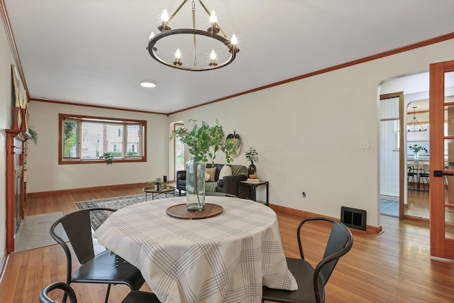 dining space featuring crown molding, visible vents, a chandelier, and light wood finished floors