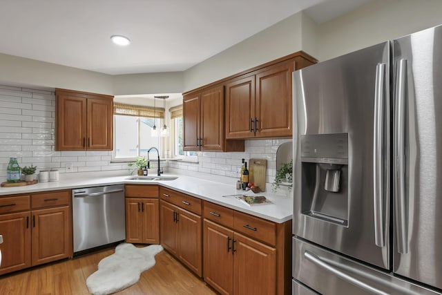 kitchen featuring a sink, appliances with stainless steel finishes, light wood-style floors, and brown cabinets